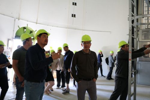 Eine Gruppe Menschen mit gelben Helmen stehen im Inneren einer Windkraftanlage.