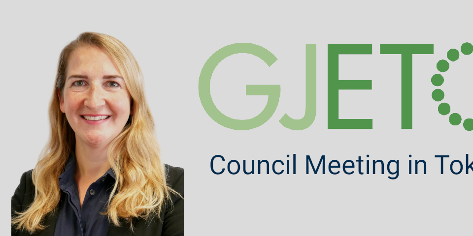 Das Bild zeigt ein Porträt von Kathrin Goldammer auf grauem Hintergrund, daneben die Abkürzung GJETC und die Worte Council Meeting in Tokyo