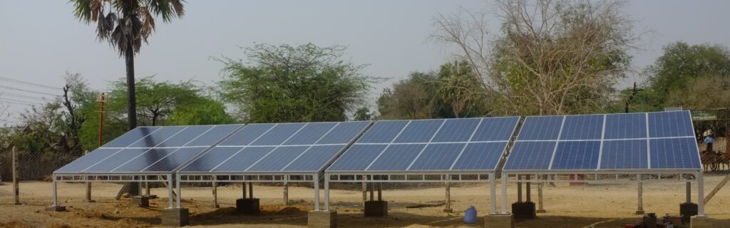 Das Foto zeigt eine Mini-Grid-Anlage, Solarmodule. Im Hintergrund sind Palmen.