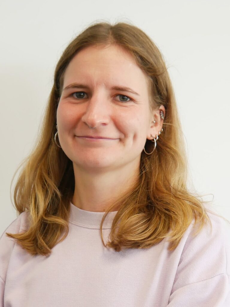 DAs Foto zeigt eine blonde Frau mit schulterlangen Haaren, die freundlich in die Kamera blickt.