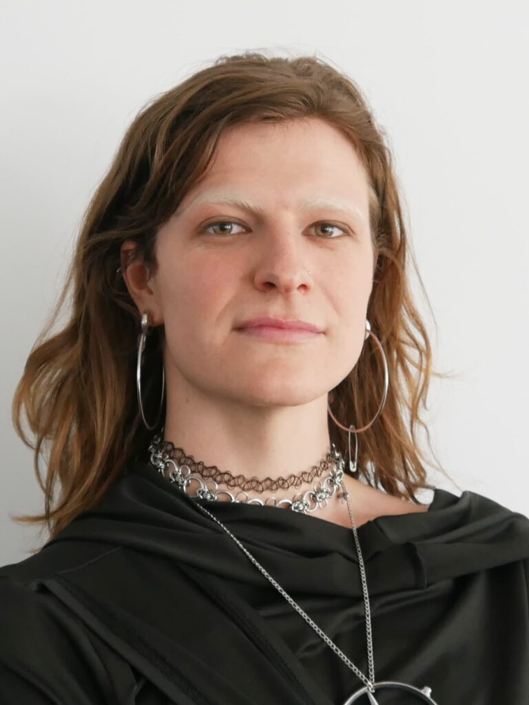 Das Foto zeigt eine Person mit langen dunkelblonden Haaren, die freundlich in die Kamera guckt